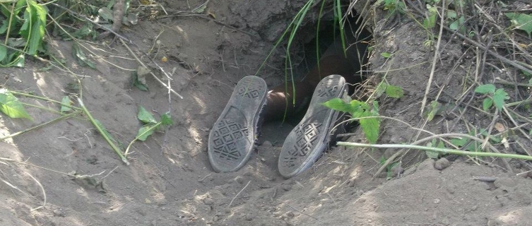 Hunter N!abi wriggles into a tiny porcupine burrow